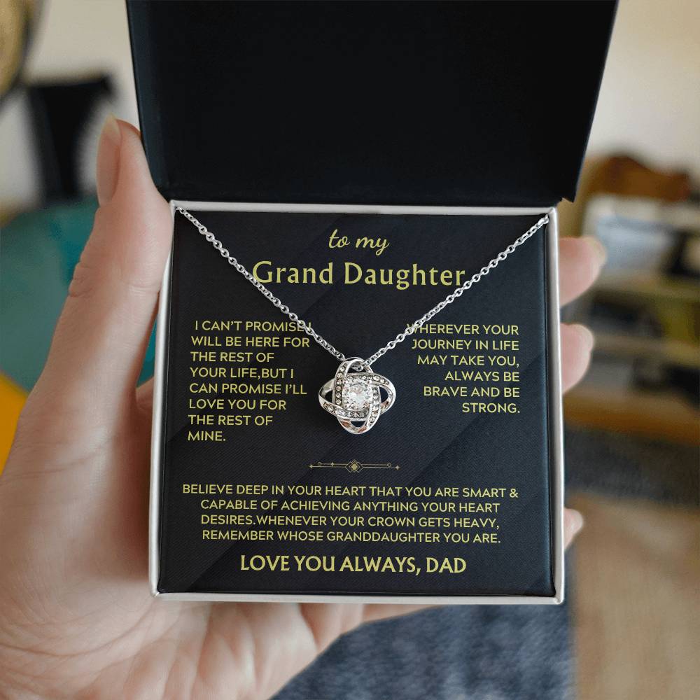 Hand holding an open box with a silver Love Knot necklace and message card