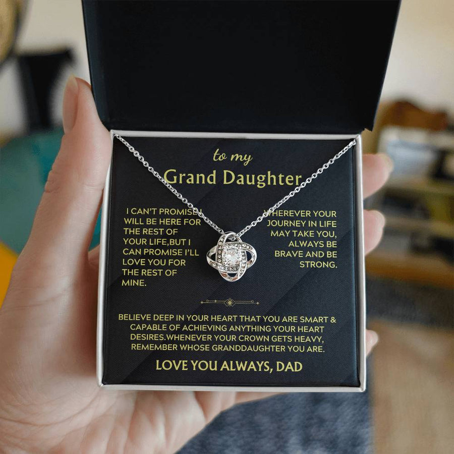 Hand holding an open box with a silver Love Knot necklace and message card