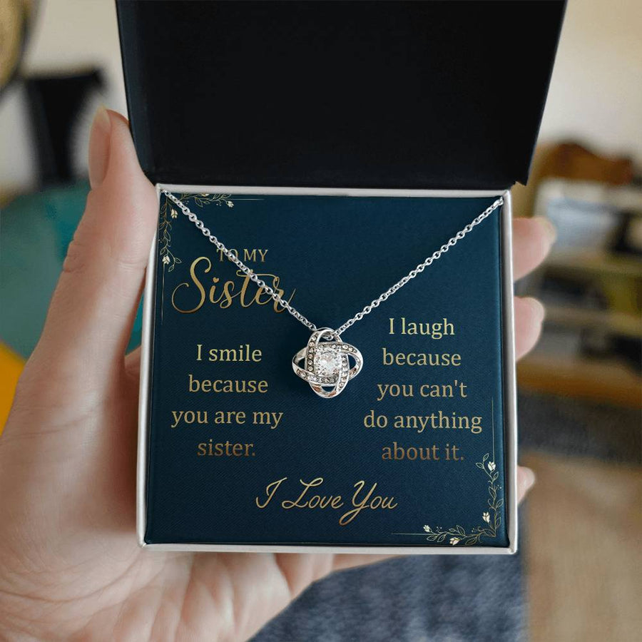 Hand holding an open jewellery box containing a sister message card necklace