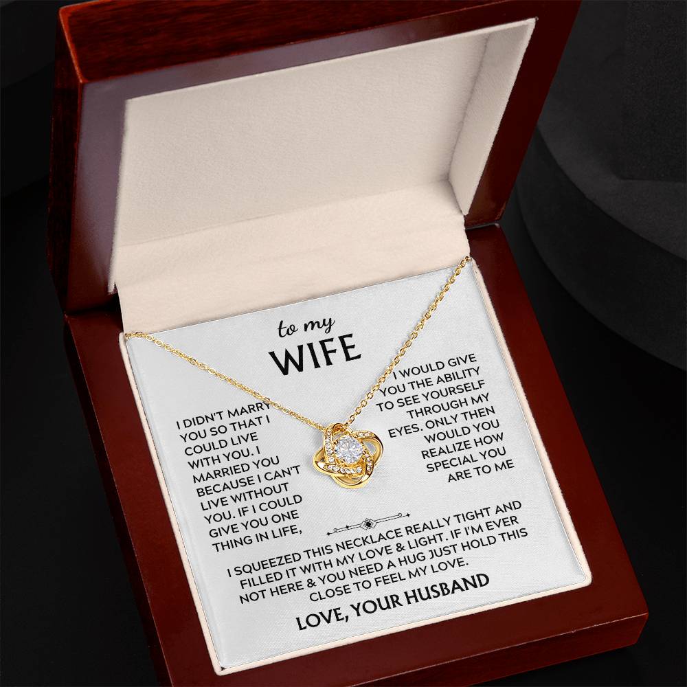 Angled view of a gold Love Knot necklace and message card in a mahogany box