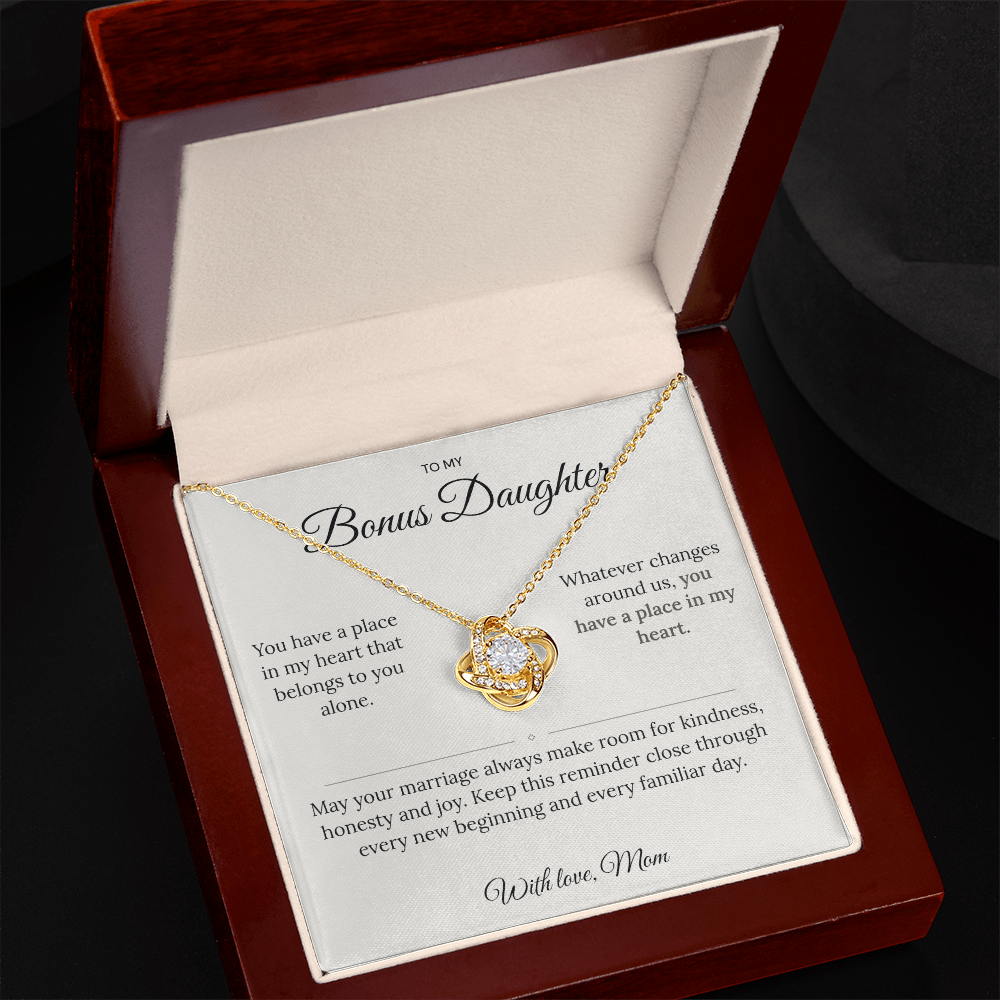 Angled view of a gold Love Knot necklace and bonus daughter message card in an open jewellery box