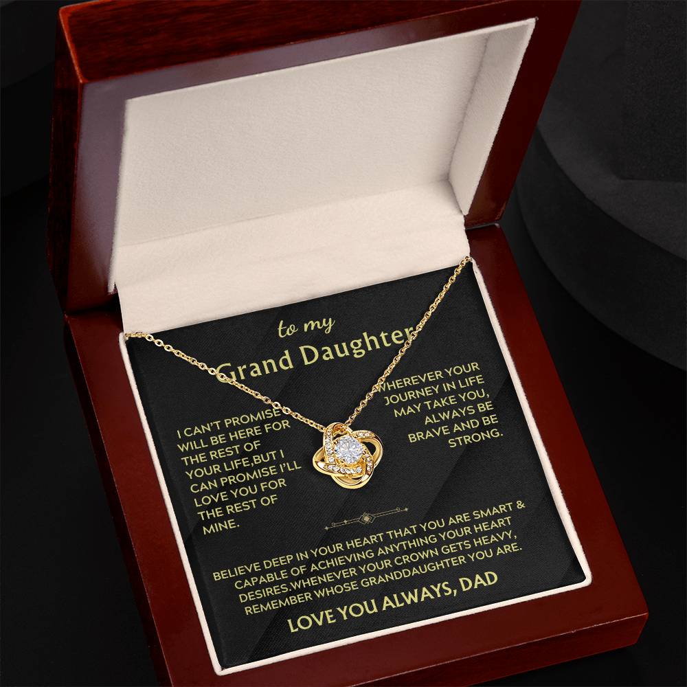 Angled view of a gold Love Knot necklace and message card in a mahogany box