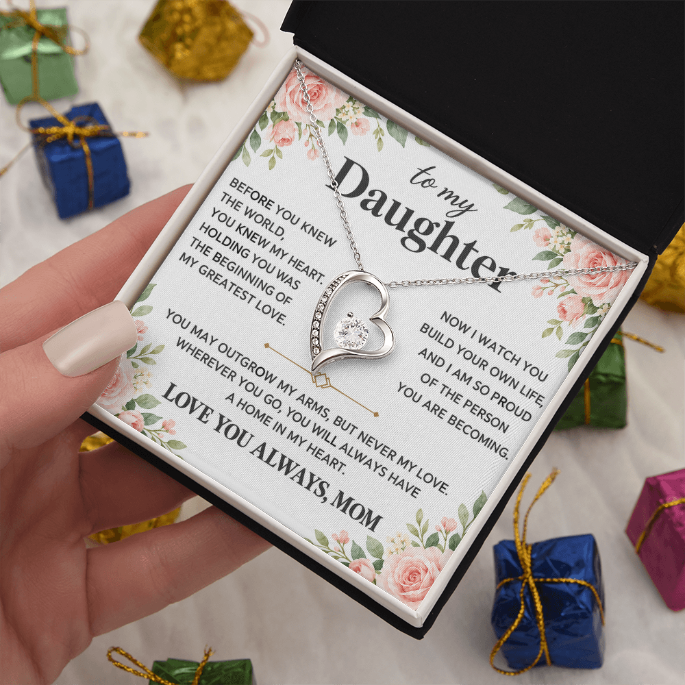 Heart pendant necklace displayed in an open black box with the Daughter message card and wrapped gifts nearby.
