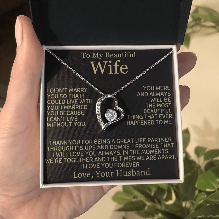 Open jewellery box held in a hand, showing a heart pendant and wife message card.