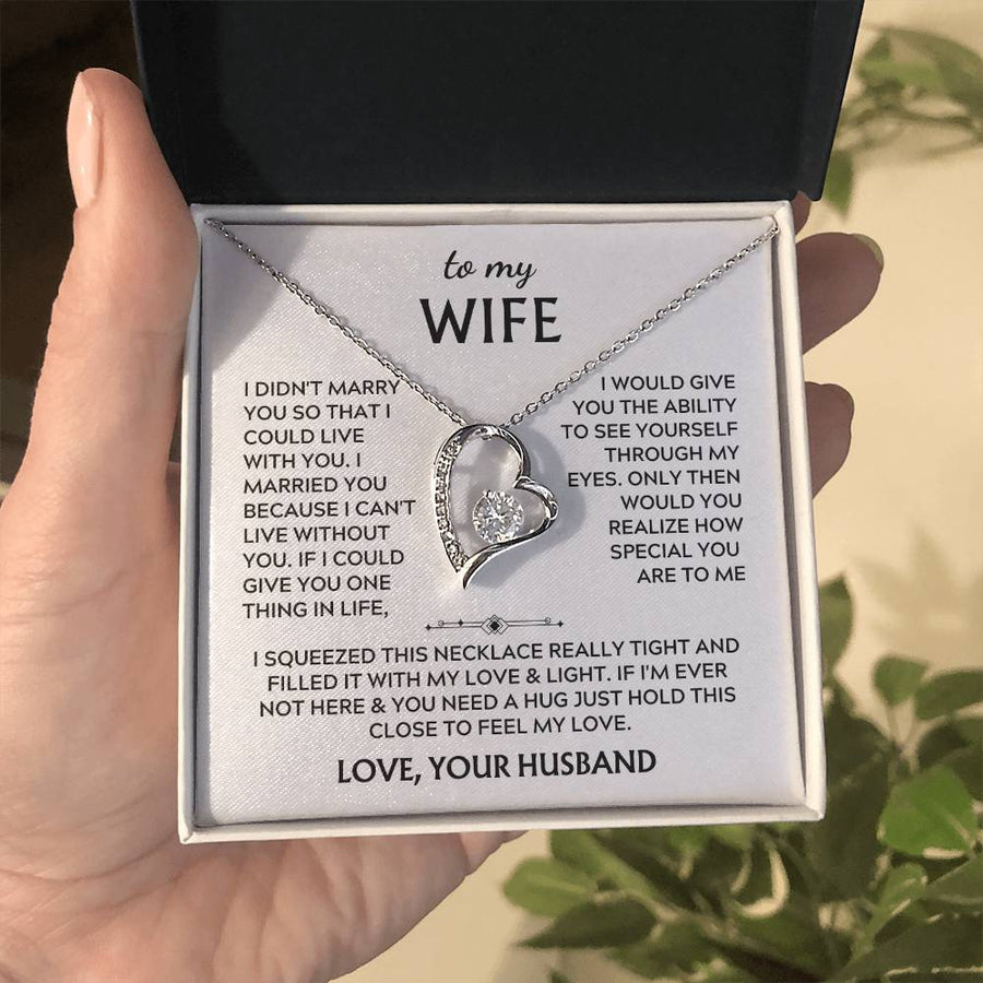Open presentation box held in a hand, showing a silver heart necklace and printed wife message card.