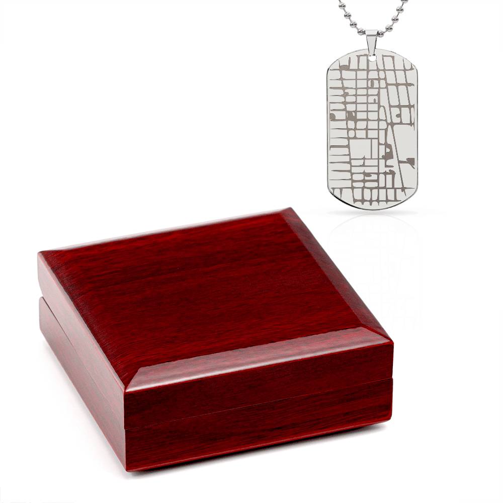 Silver map dog tag necklace displayed above a dark wooden presentation box