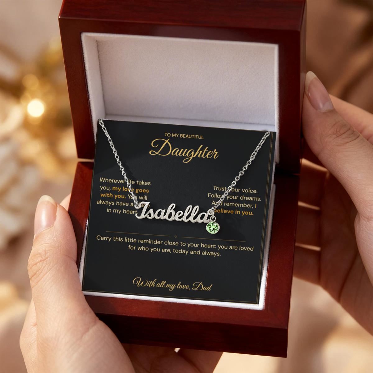 Hands holding an open mahogany-style box with an Isabella name necklace and Daughter message card from Dad.